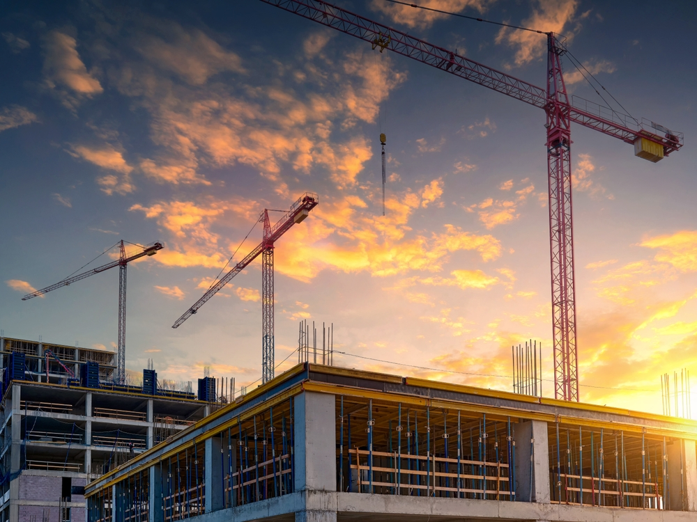 Cranes over a residential tower at sunset